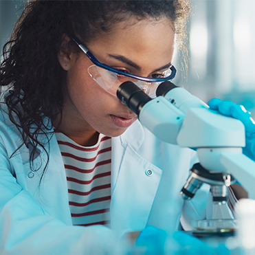 Cientista mulher olhando pelo microscópio.