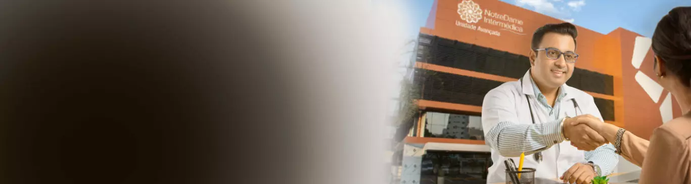 Médico cumprimenta paciente e ao fundo uma unidade NotreDame Intermédica