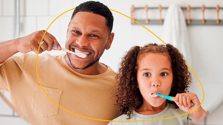 Homem e criança escovando os dentes