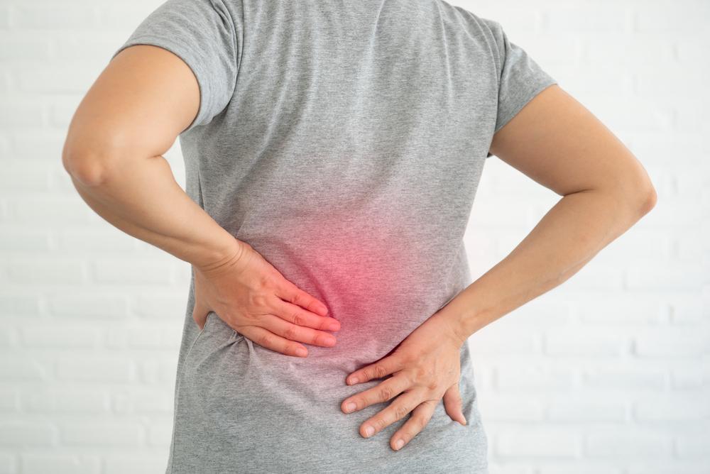 Pessoa segurando a região lombar, indicando desconforto nas costas associado à osteoporose.