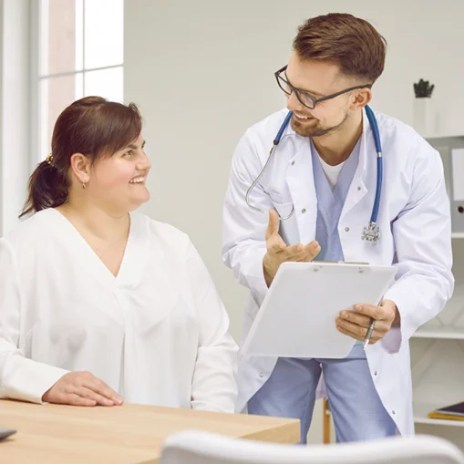 Paciente sendo atendida por médico, ambos sorrindo