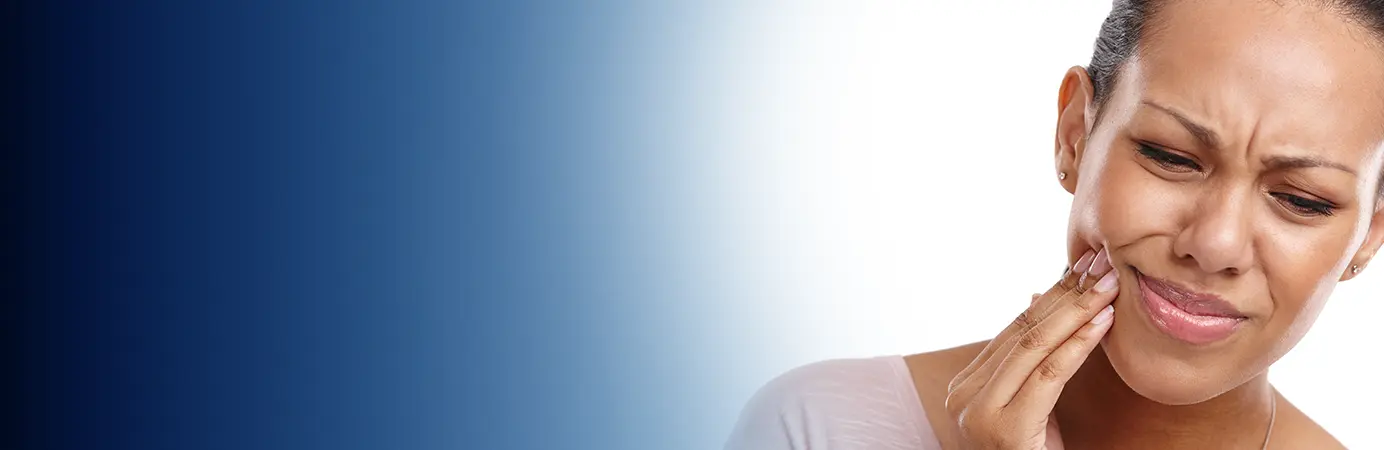 Mulher com a mão no rosto por causa de dor