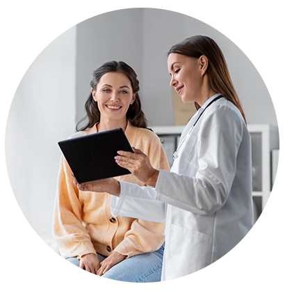Médica mostrando informações em um tablet para paciente sorridente durante a consulta.